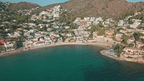 Aerial drone footage of Moraira coastal town and beach with turquoise Mediterranean water, houses, and mountains in the background. Scenic summer view of Costa Blanca, Spain. - Powered by Shutterstock - Get 15% off with code: PIKWIZARD15