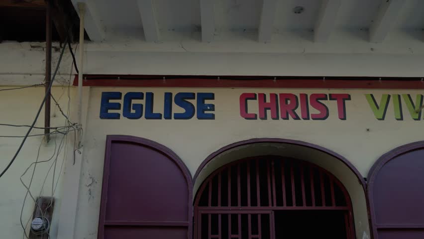 Close-up of colorful hand-painted sign for Eglise Christ Vivant, Living Christ Church, on building, Haiti