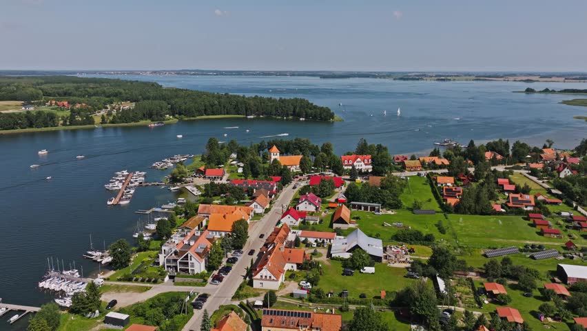 Bright summer aerial view of Rydzewo on Niegocin Lake showing boats and rooftops