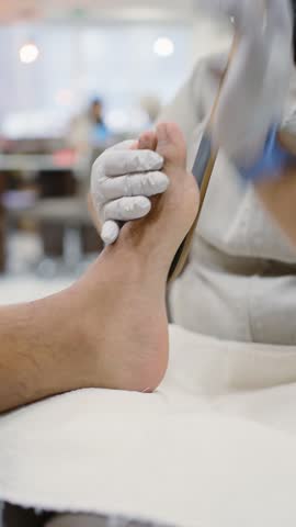 Professional pedicurist filing a man's feet during a spa treatment in a modern beauty salon