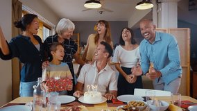 Storytelling image of a Family reunited at home for lunch on the holidays. Family members celebrating eating good food, sharing love and emotions. Singing birthday songs and blowing on candles - Powered by Shutterstock - Get 15% off with code: PIKWIZARD15