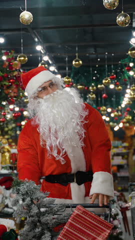 Santa Claus pushing a shopping cart full of Christmas gifts and decorations