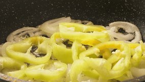 White onion rings and yellow bell peppers fried in a frying pan with vegetable oil. Medium shot. - Powered by Shutterstock - Get 15% off with code: PIKWIZARD15