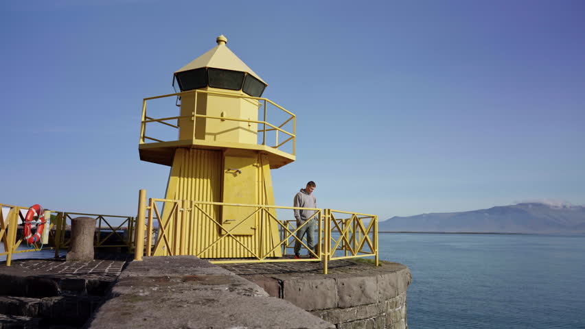 Man near Yellow Lighthouse Reykjavik Iceland Coastal View