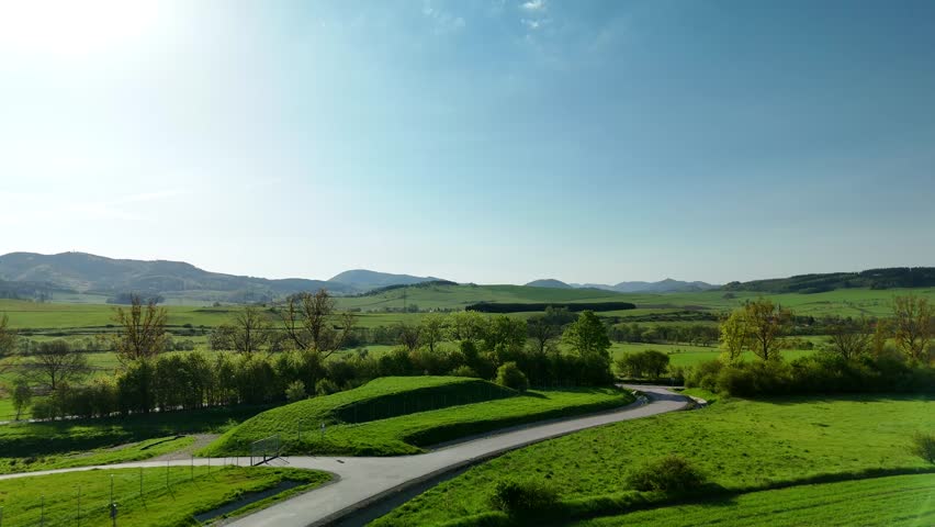 Charming Polish Village in Mountain Region with Country Road, Green Fields, and Blue Sky