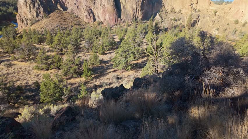 A vast, stunning panoramic view of the towering, dramatic volcanic rock formations of Smith Rock State Park and the meandering emerald waters of the Crooked River
