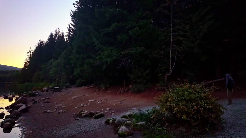 A classic, breathtaking scenic view of the majestic Mount Hood volcano perfectly reflected in the calm, glassy waters of Trillium Lake, illuminated by the warm, golden light of sunrise.