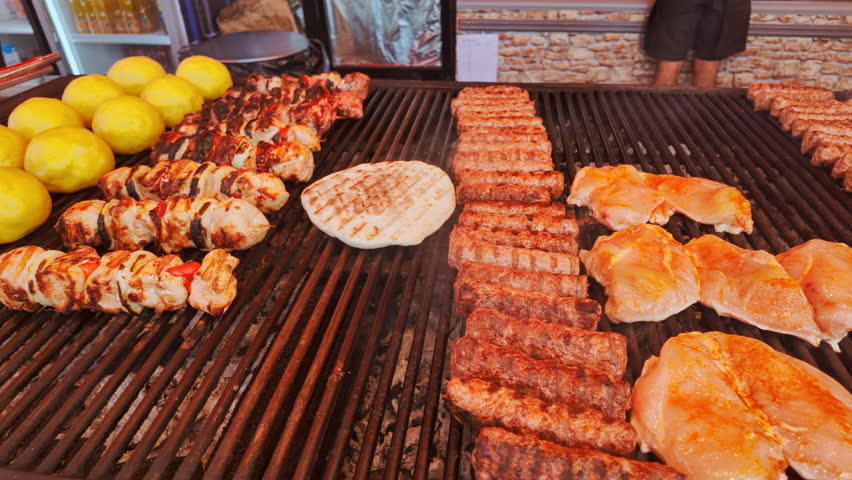 Vibrant scene at a street food stall of a traditional market, containing sausages and other types of meats and street food meals
