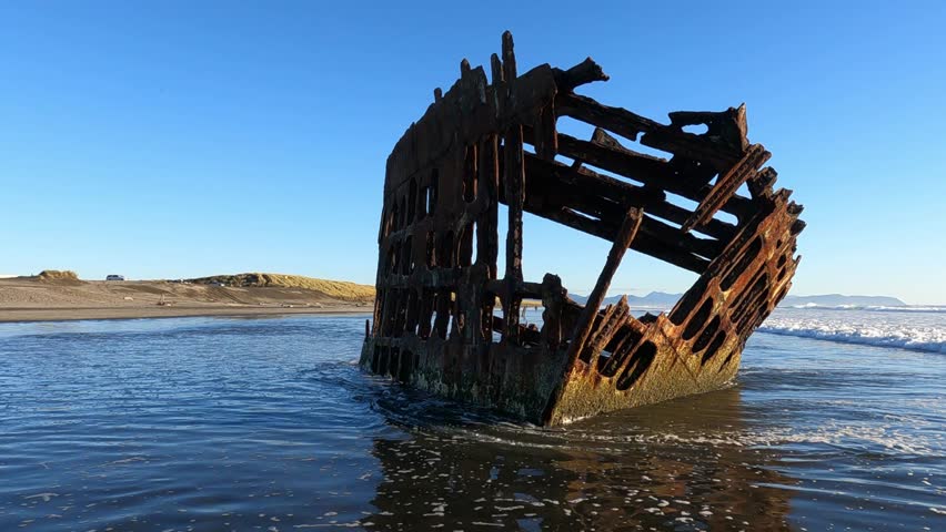 A poignant view of the rusted skeletal remains of the Peter Iredale shipwreck, standing sentinel on the sandy beach within Fort Stevens State Park on the Oregon Coast
