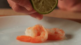 A hand squeezes a fresh lime, with a drop of juice falling onto cooked shrimp - Powered by Shutterstock - Get 15% off with code: PIKWIZARD15
