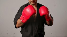 Close up of a man practicing Wing Chun in a black kimono. Martial arts master in red boxing gloves training in a martial arts training room. - Powered by Shutterstock - Get 15% off with code: PIKWIZARD15