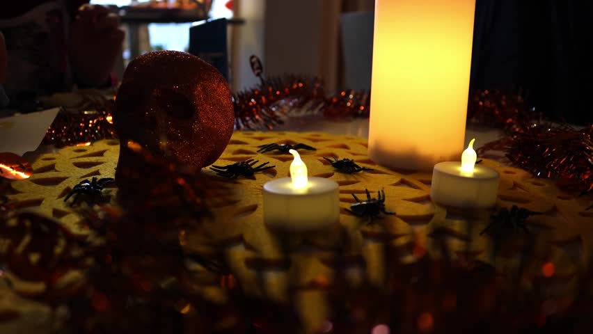 People sitting at a Halloween-themed table eating spooky snacks, with a decorative skull and burning candles creating a dark festive atmosphere. Warm candlelight and horror-style decorations captured  - Powered by Shutterstock - Get 15% off with code: PIKWIZARD15
