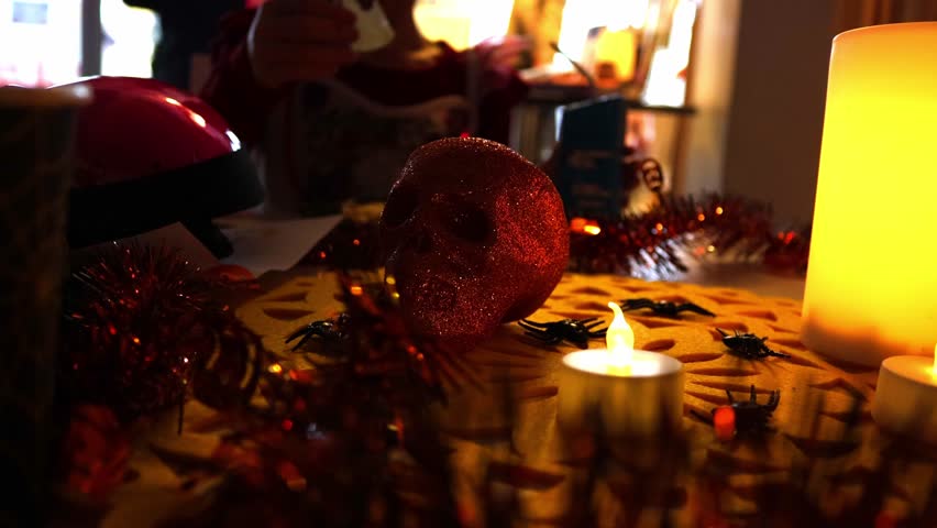 People sitting at a Halloween-themed table eating spooky snacks, with a decorative skull and burning candles creating a dark festive atmosphere. Warm candlelight and horror-style decorations captured  - Powered by Shutterstock - Get 15% off with code: PIKWIZARD15