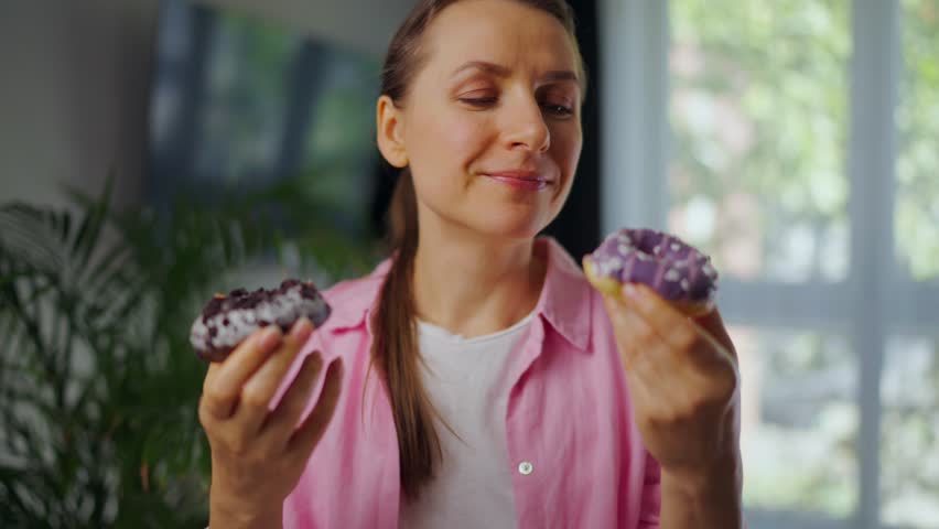 Woman with eating disorder eating two donuts with pleasure and at the same time