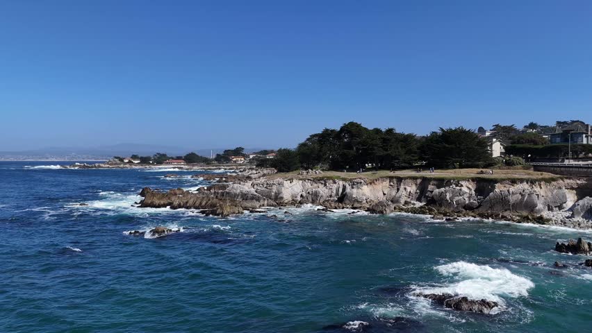 Aerial drone footage of Lovers Point in Monterey Bay showcasing the rugged California coastline and includes close-up freeze frames of distinctive black oystercatcher seabirds in flight.