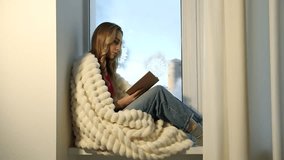 Woman wrapped in plaid reading book on window sill at home. Cozy winter day - Powered by Shutterstock - Get 15% off with code: PIKWIZARD15