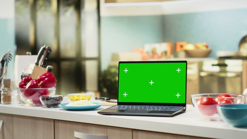 Isolated screen on laptop in modern kitchen used for cooking homemade pizza, ingredients like pepperoni and sauce sit beside utensils and jars on the countertop. Delicious food prep scene.