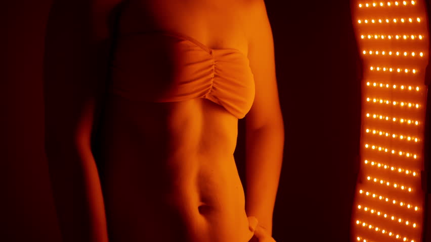 Woman enjoying a skin care treatment near red light therapy panel at home 