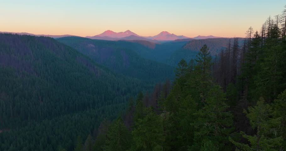 Aerial drone flight capturing Three Sisters and surrounding valleys at dusk