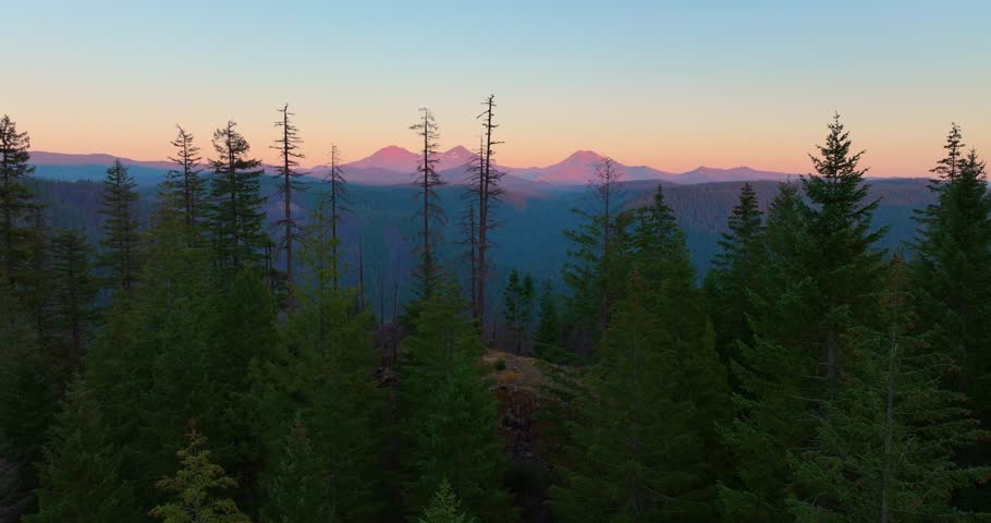 Drone view showing warm golden light on the Three Sisters peaks in Oregon