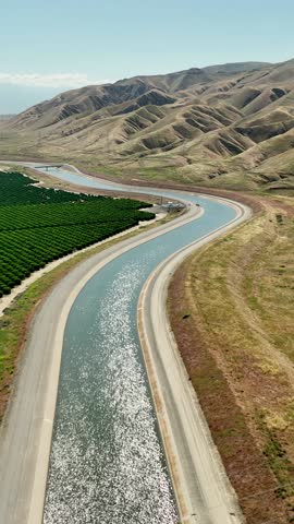Aerial of farms along an aqueduct running through California's Central Valley north of Los Angeles. Vertical video,