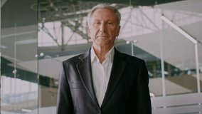 Senior businessman confidently stands in modern office environment - Powered by Shutterstock - Get 15% off with code: PIKWIZARD15