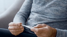 Senior man checking temperature at home while relaxing in cozy setting - Powered by Shutterstock - Get 15% off with code: PIKWIZARD15