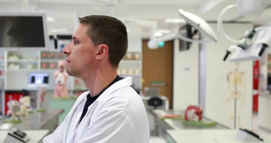 Camera pulling in, clinician rotating to camera with HUD charts shifting and showing medical data. Laboratory, researcher, anatomy, mannequin, labcoat, monitor, workbench