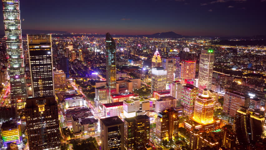 Aerial hyperlapse of Downtown Taipei at dusk, the vibrant capital city of Taiwan, with 101 Tower standing out amid skyscrapers in XinYi Commercial District and city lights dazzling under twilight sky