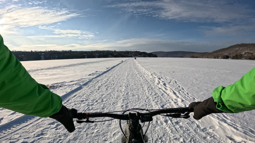 Winter Wonderland. Fat Biking Across a Frozen Lake - Scenic Adventure Cycling Experience. Exploring Frozen Lake Trails on a Fat Bike - Thrilling Winter Ride in Snowy Landscape.