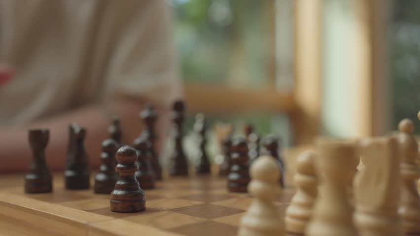 Hand moving knight on chessboard in bright, thoughtful atmosphere