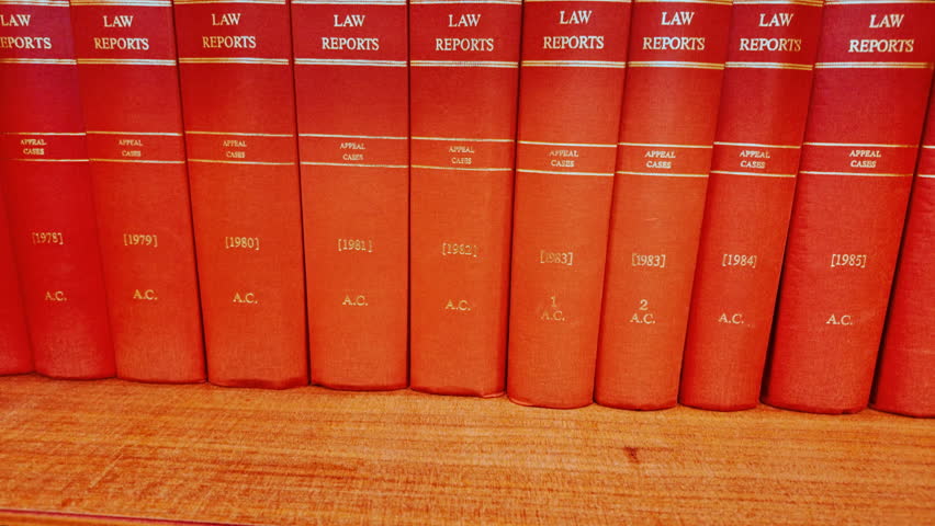 Close up of various red law books containing reports of important legal cases, stacked on a shelf with gilt titles and pristine spines
