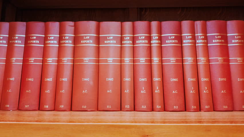 Close up of various red law books containing reports of important legal cases, stacked on a shelf with gilt titles and pristine spines
