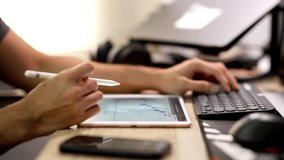 Business analytics concept with a person analyzing financial data on a digital tablet using a stylus while typing on a keyboard, showing charts, graphs, and data analysis in an office workspace. - Powered by Shutterstock - Get 15% off with code: PIKWIZARD15