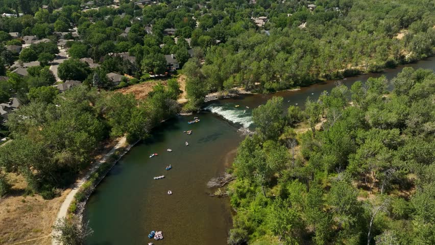 People floating in innertubes on the Boise River by whitewater rapids. Aerial view
