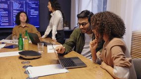 Diverse coworkers sitting around conference table in modern office working on laptop and discussing project ideas showing teamwork collaboration creativity and professional business communication - Powered by Shutterstock - Get 15% off with code: PIKWIZARD15