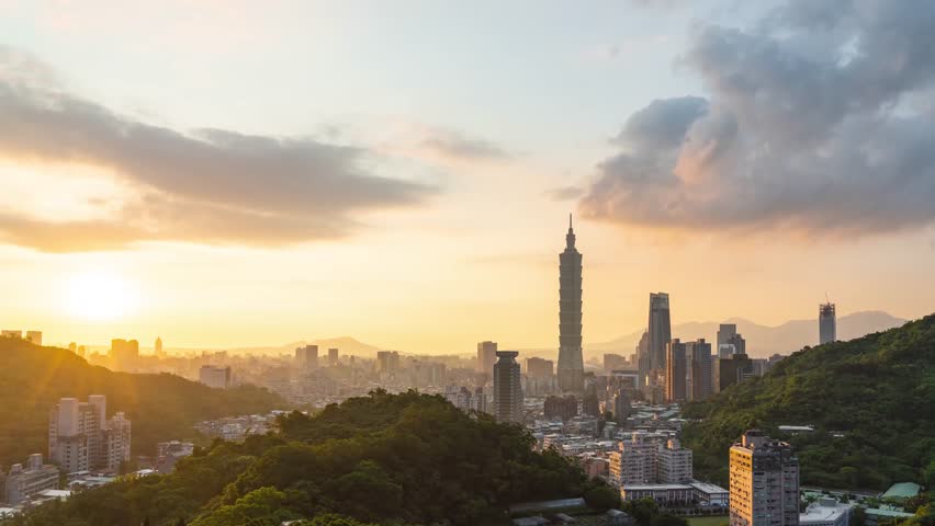 Aerial view of tall skyscrapers in a modern city glowing under orange sunset light.