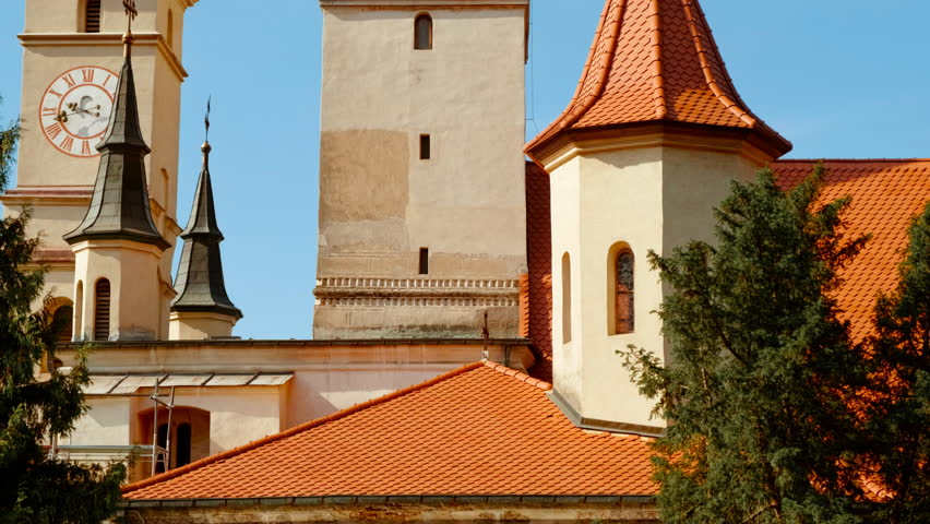 St Nicholas Church, Brasov, Transylvania, Romania, with a tall tower, painted porch and quiet square

