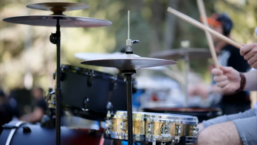 Close-up of a man playing red drums outdoors, showcasing live music, percussion performance, and vibrant musical expression.