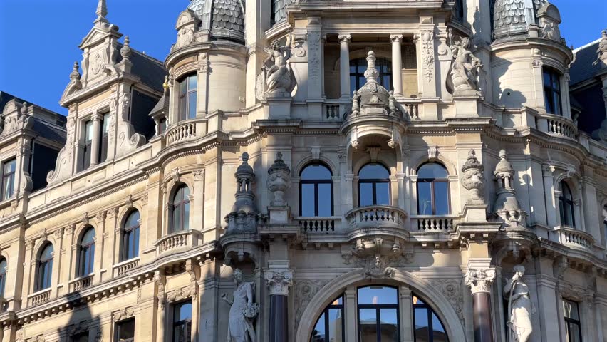 Grand historic building featuring ornate architecture and sculptures under a clear blue sky in Antwerp, Belgium