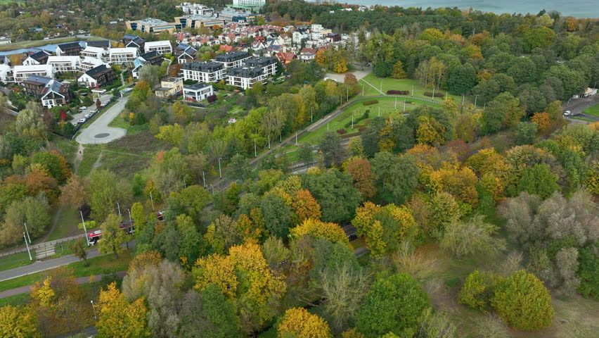Drone shot of Jelitkowo district in Gdańsk with tram tracks, park, and Baltic Sea coastline.