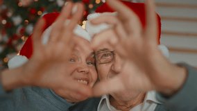 Aged man and woman showing heart symbol by palms, closeup, Christmas holiday. Happy elderly married couple celebrating Xmas and new year, enjoying fabulous atmosphere and love, long happy marriage - Powered by Shutterstock - Get 15% off with code: PIKWIZARD15