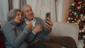 Aged spouses celebrating Christmas and New year, calling by mobile app from home . Portrait of happy elderly man and woman smiling to frontal camera of smartphone, online chatting and congratulating - Powered by Shutterstock - Get 15% off with code: PIKWIZARD15