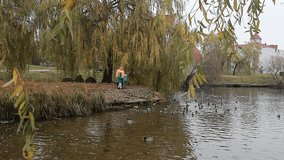 A grandmother with two grandsons, boys, are walking in the park and feeding ducks in the river. - Powered by Shutterstock - Get 15% off with code: PIKWIZARD15