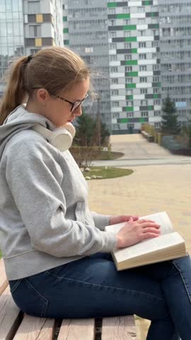 A young woman reading a book on a walk. 