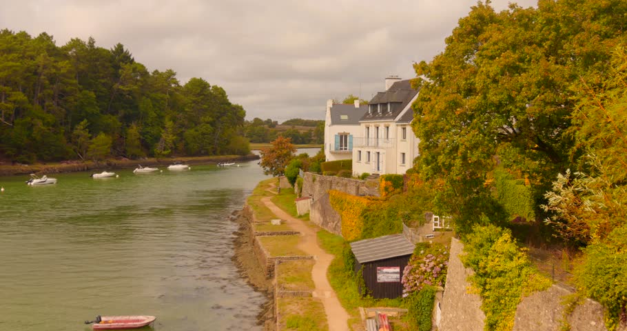 Charming riverside in Le Bono, Brittany, with boats and lush greenery