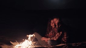 A romantic couple sits by a glowing campfire on the beach at night, cuddling under the stars. The warmth of the fire and their intimate moment create a cozy, serene atmosphere, ideal for love, travel - Powered by Shutterstock - Get 15% off with code: PIKWIZARD15