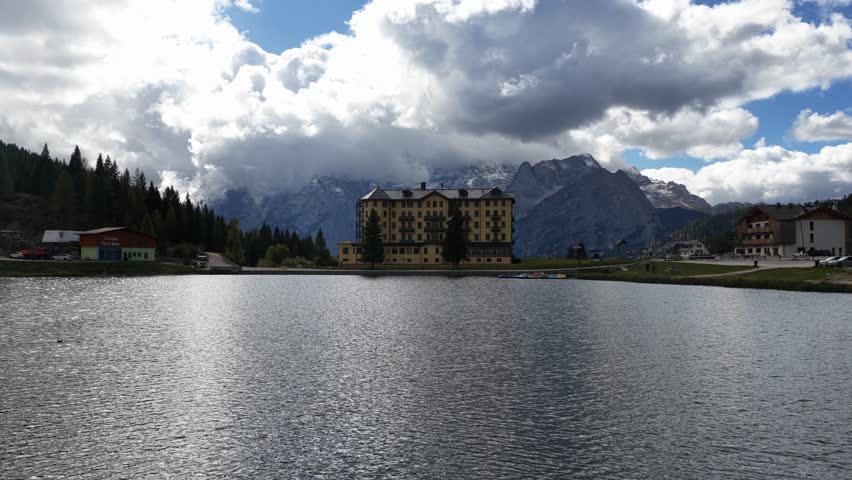 Lake Misurina, the romantic heart of the Dolomites, crystal clear waters reflect the majestic peaks that surround it, such as the Sorapiss group. Aerial drone video, daytime.