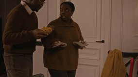 Handheld shot of young black couple communicating while setting table with cutlery and snacks preparing for Thanksgiving celebration at home - Powered by Shutterstock - Get 15% off with code: PIKWIZARD15