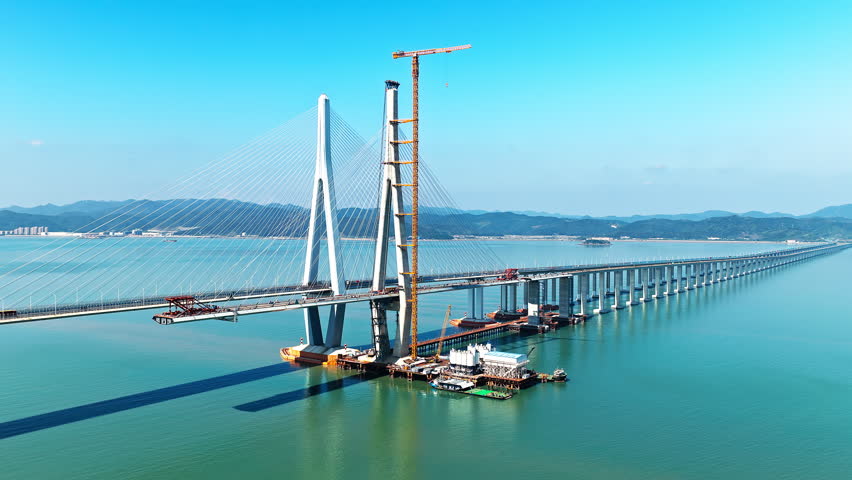 Aerial shot of a massive cable-stayed bridge under construction, an impressive feat of engineering and infrastructure over the sea. Famous Xiangshan Port Cross-Sea Bridge is located in Ningbo, China.